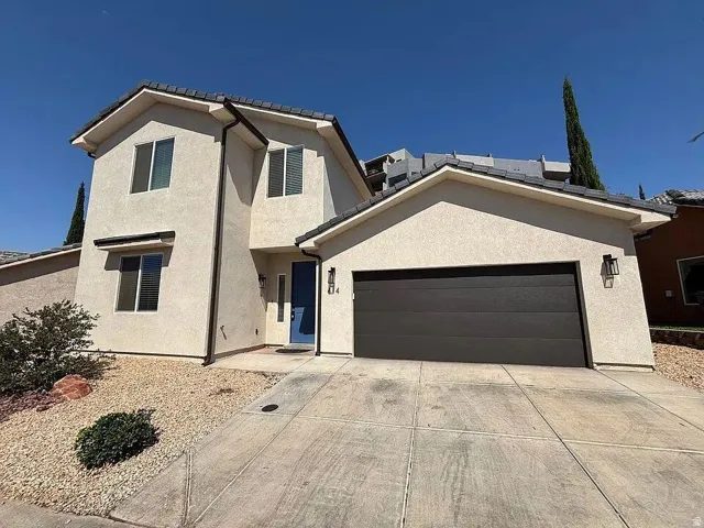View of front of house featuring a garage, concrete driveway, stucco siding, and a tiled roof