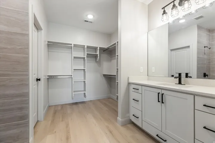 White shaker vanity with black hardware, integrated sink, and a large mirror