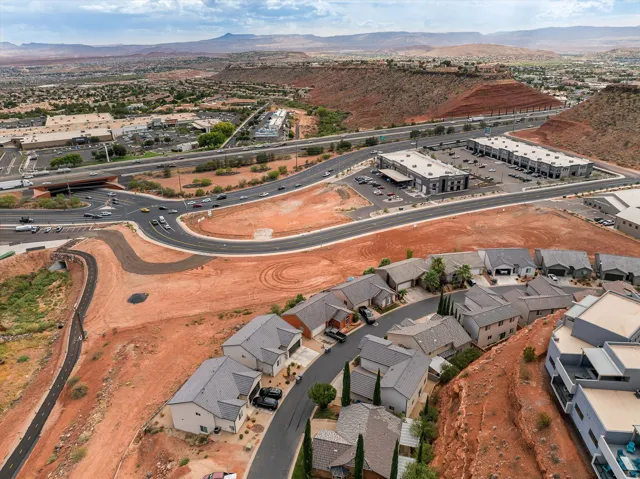 Residential development with paved roadways, adjacent commercial structures, and distant mountainous terrain