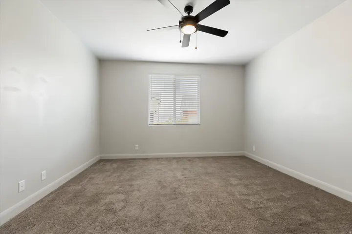 Recessed window with horizontal blinds, overhead ceiling fan with lighting, and neutral carpeting