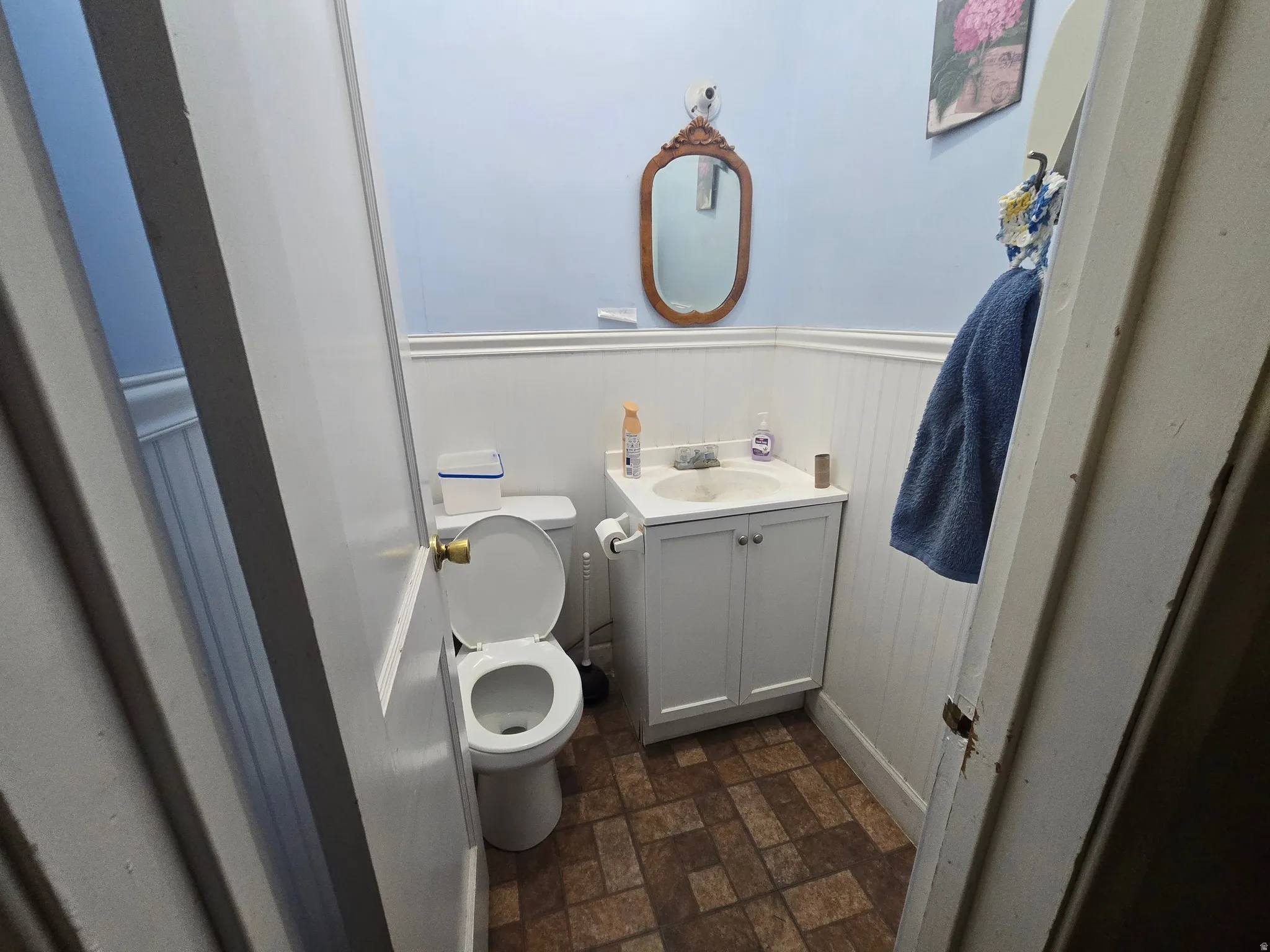Bathroom with a wainscoted wall, brick patterned flooring, and vanity