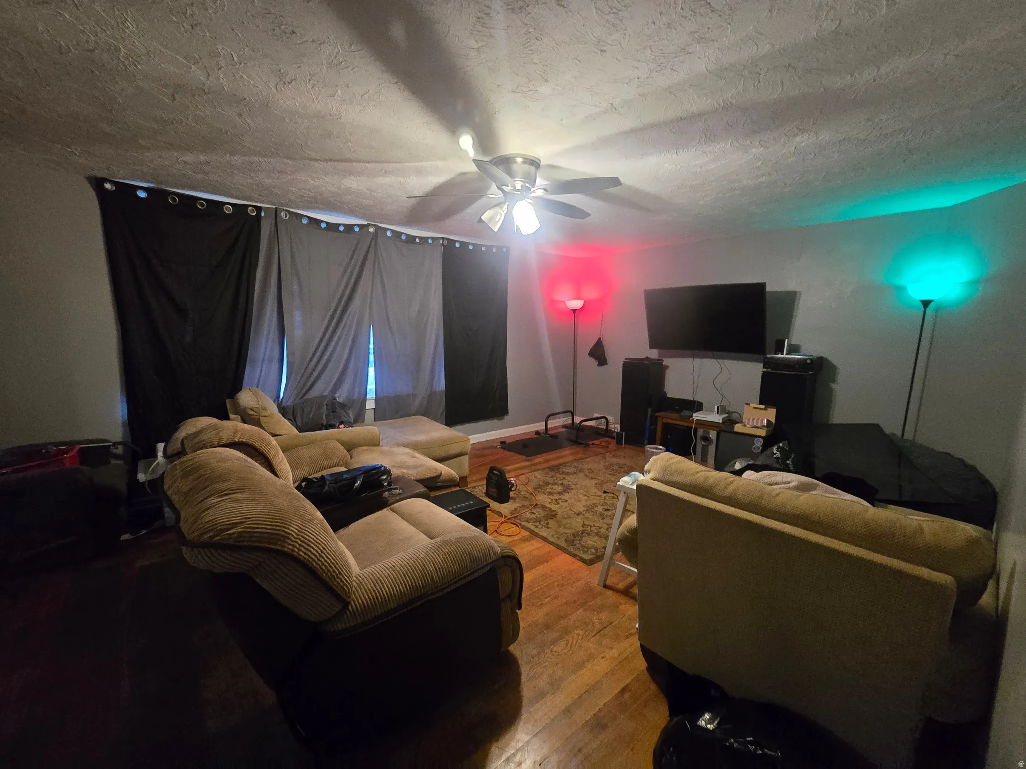 Living room featuring hardwood / wood-style flooring, a ceiling fan, and a textured ceiling