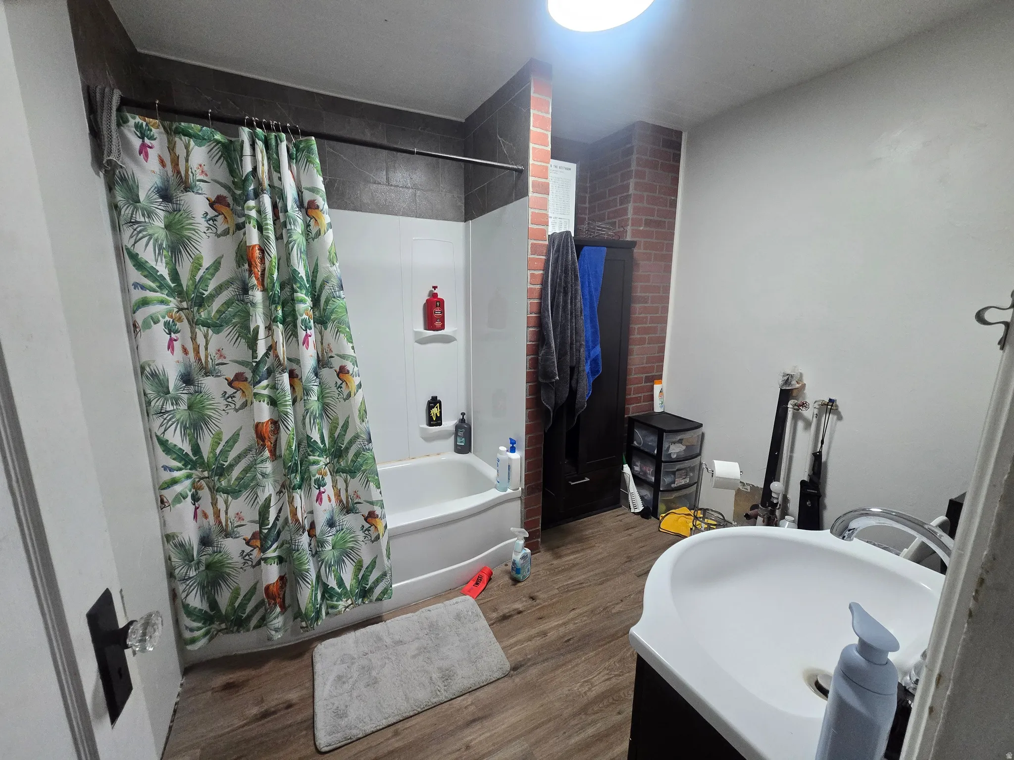 Full bath featuring vanity, shower / tub combo with curtain, and wood finished floors