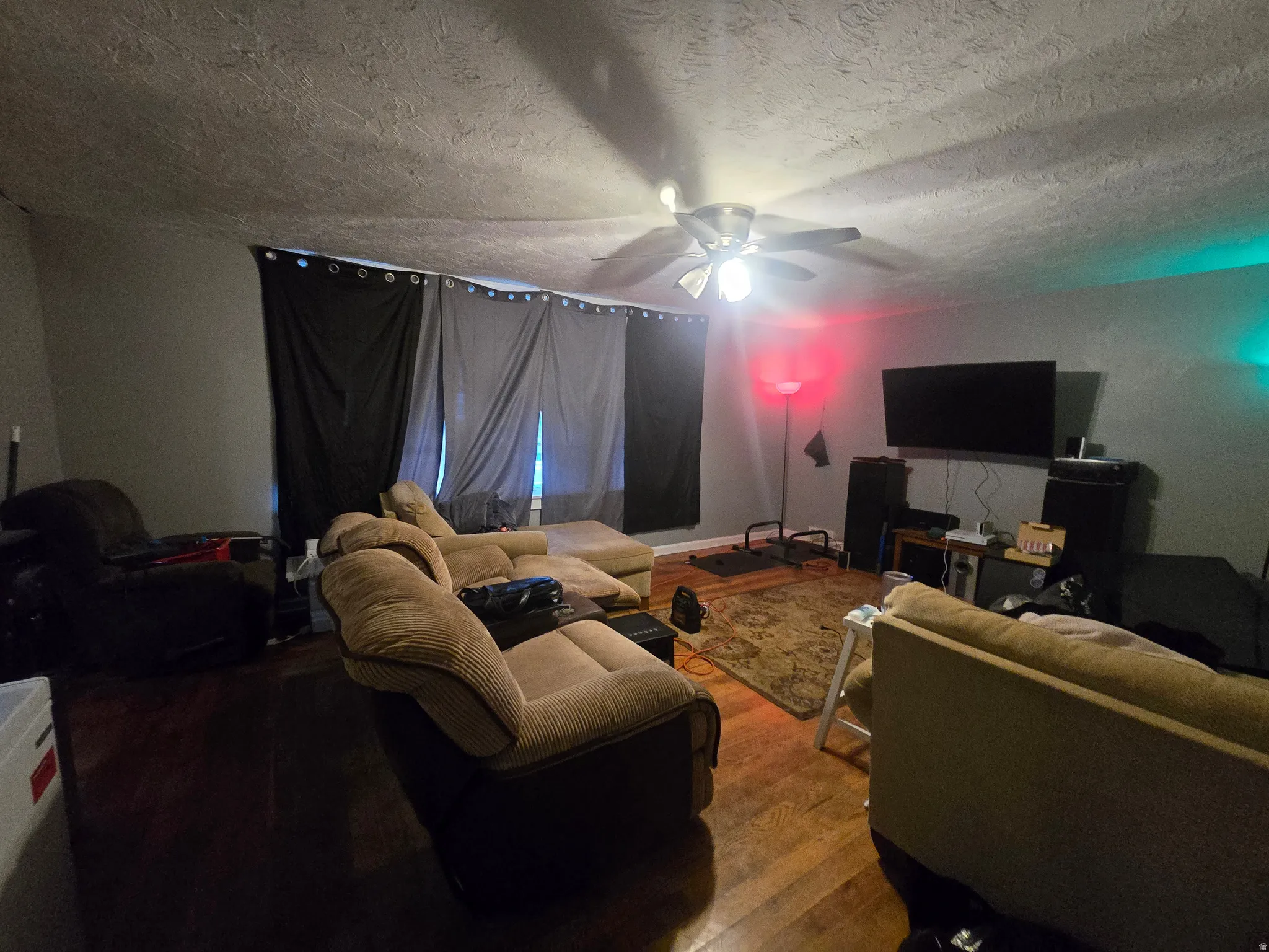 Living area with hardwood / wood-style floors, ceiling fan, and a textured ceiling