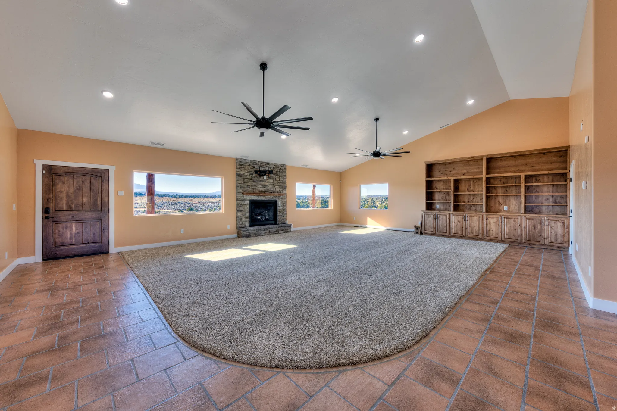 Unfurnished living room featuring a fireplace, recessed lighting, ceiling fan, vaulted ceiling, and dark carpet