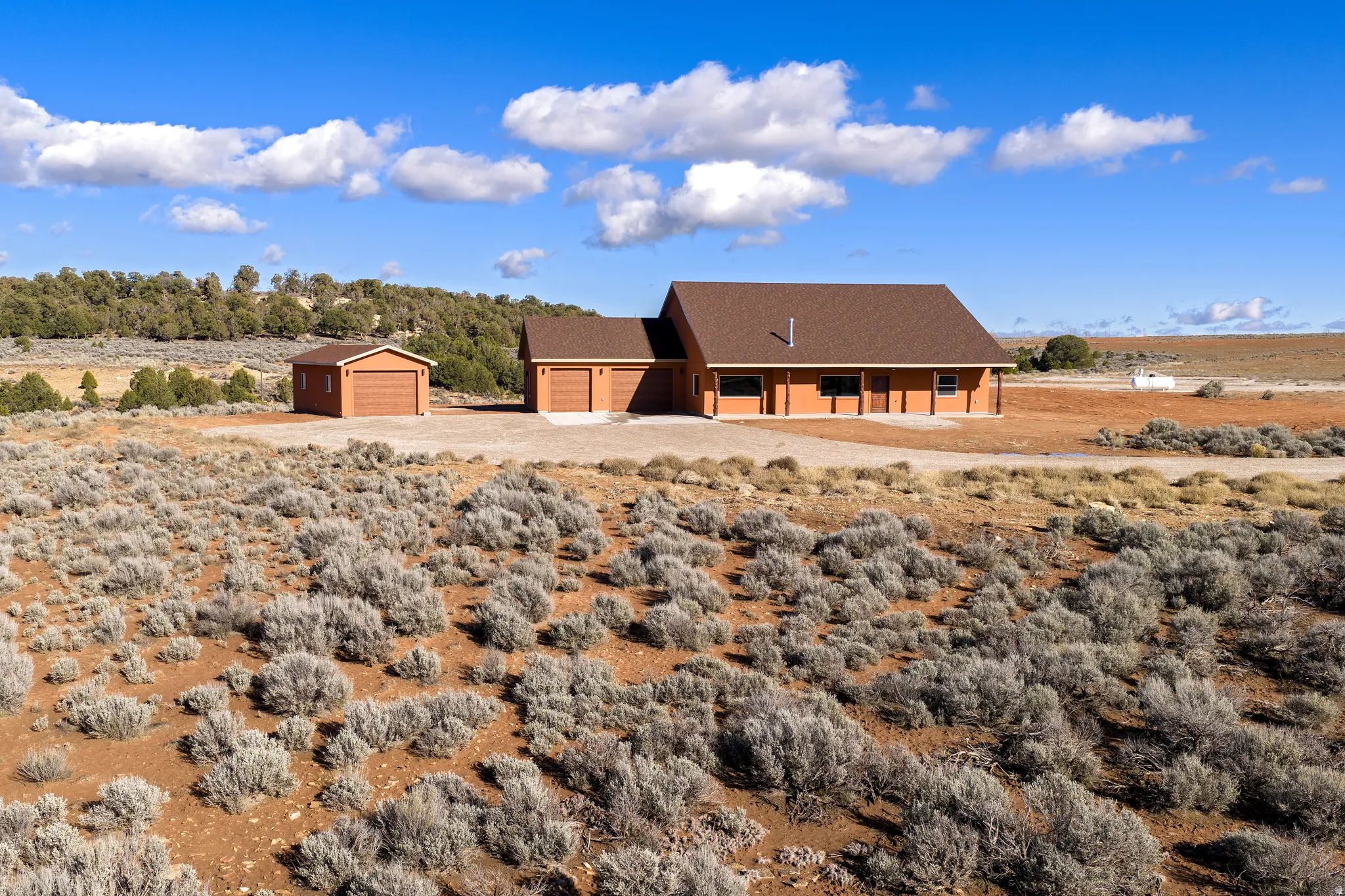 Rear view of property featuring an outdoor structure, a shingled roof, driveway, and a view of rural / pastoral area