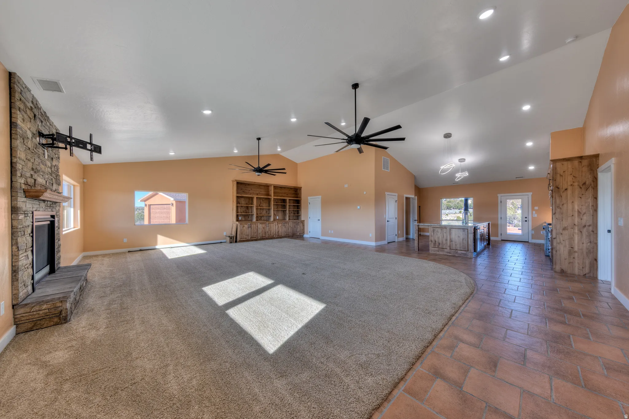 Unfurnished living room with a stone fireplace, high vaulted ceiling, a ceiling fan, dark carpet, and recessed lighting