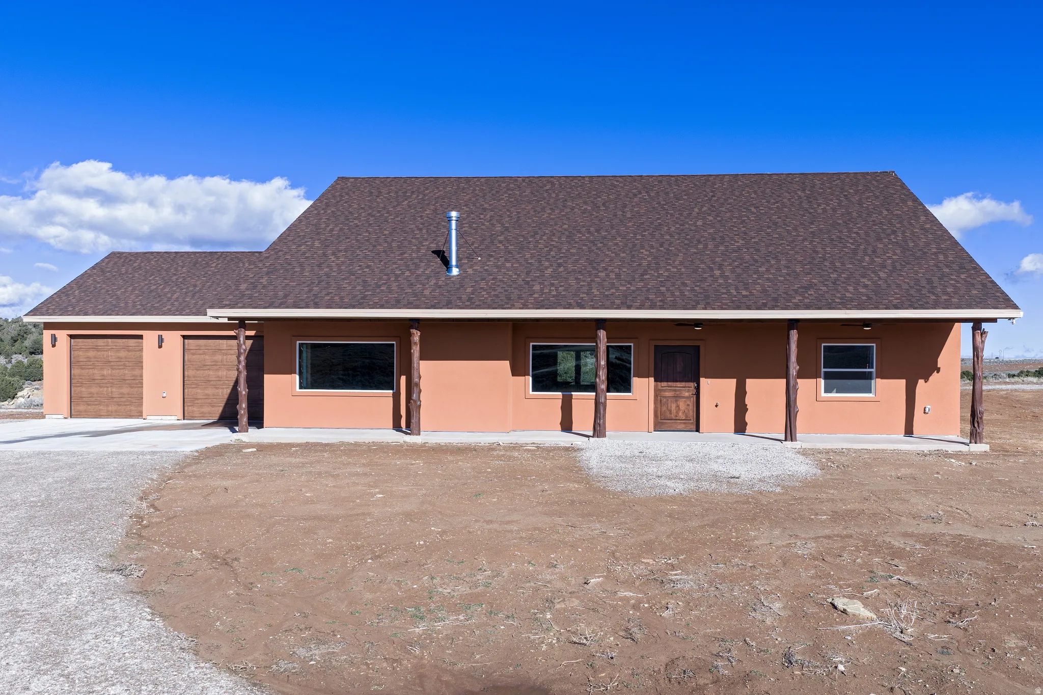 View of front of property featuring stucco siding, an attached garage, a shingled roof, and driveway