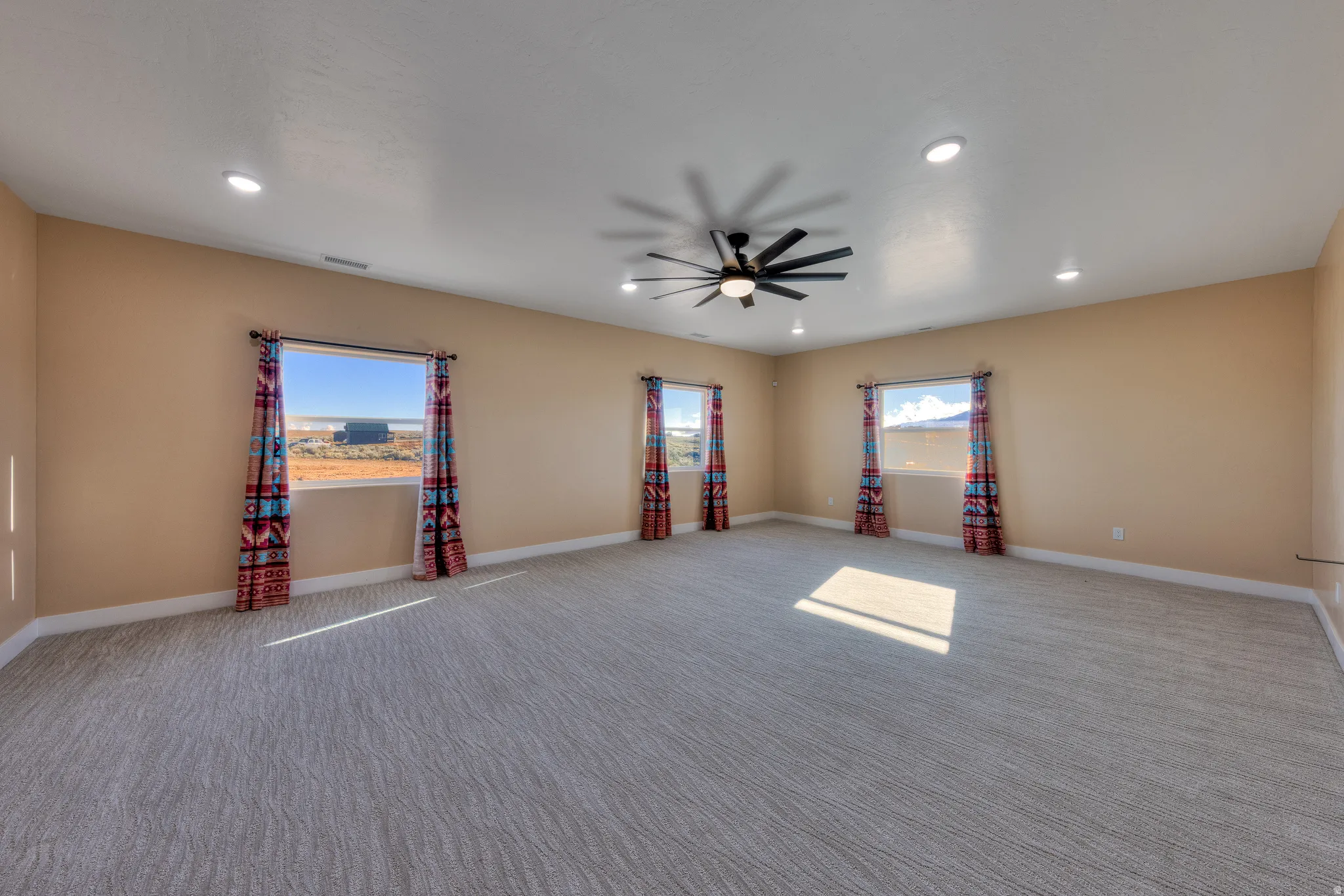 Carpeted spare room featuring healthy amount of natural light, recessed lighting, and ceiling fan