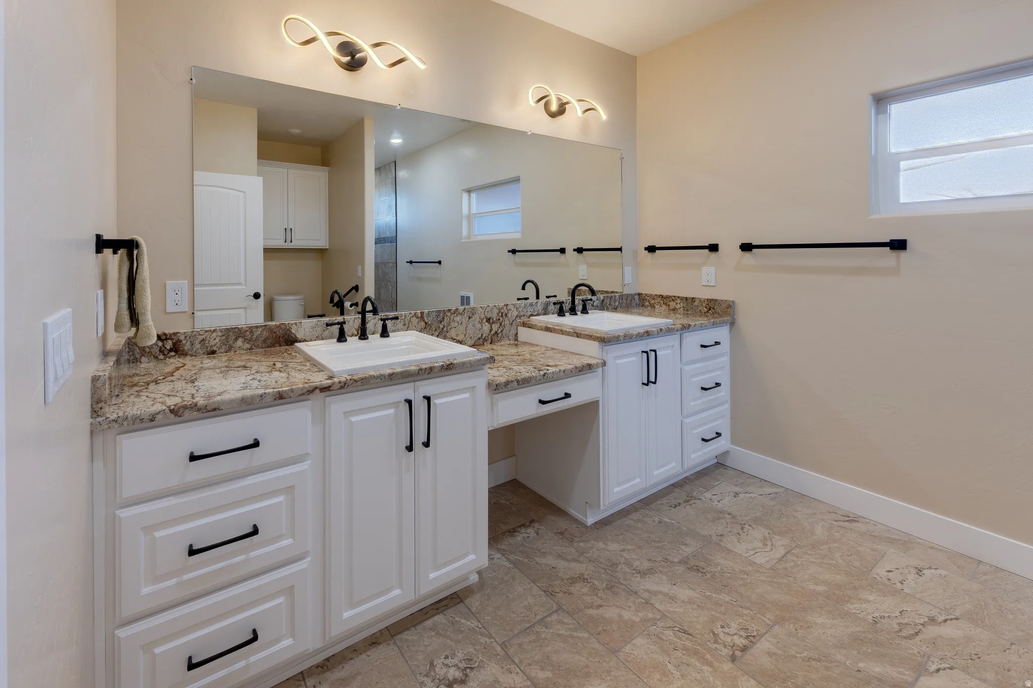Bathroom with double vanity and baseboards