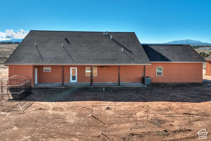 Back of house featuring a mountain view, a patio area, and roof with shingles