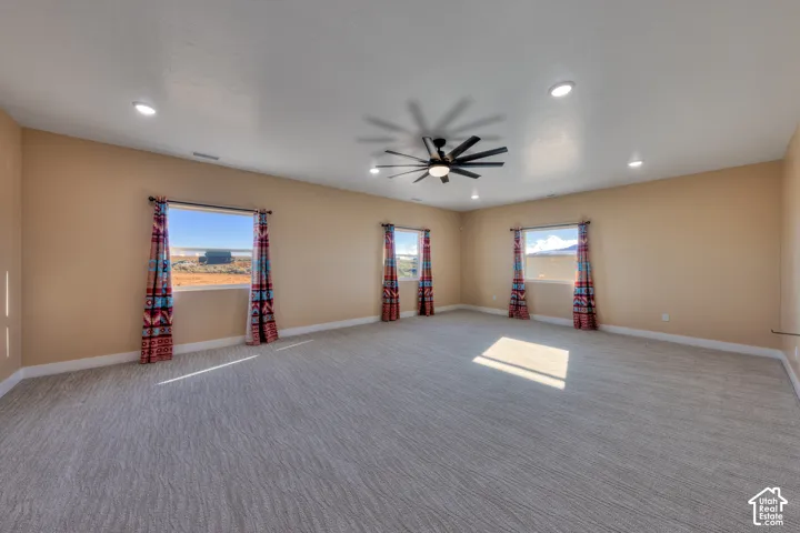 Carpeted spare room featuring healthy amount of natural light, recessed lighting, and ceiling fan