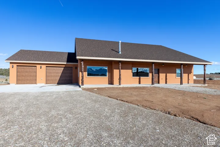 View of front of house featuring a shingled roof, concrete driveway, a garage, and stucco siding