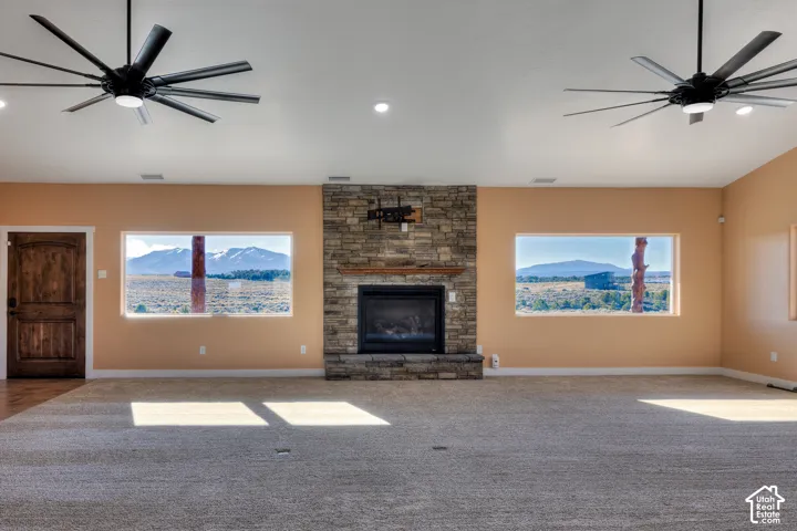 Unfurnished living room featuring ceiling fan, a fireplace, healthy amount of natural light, and recessed lighting