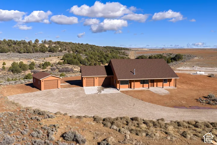 View of front facade with roof with shingles, driveway, a garage, and view of desert landscape