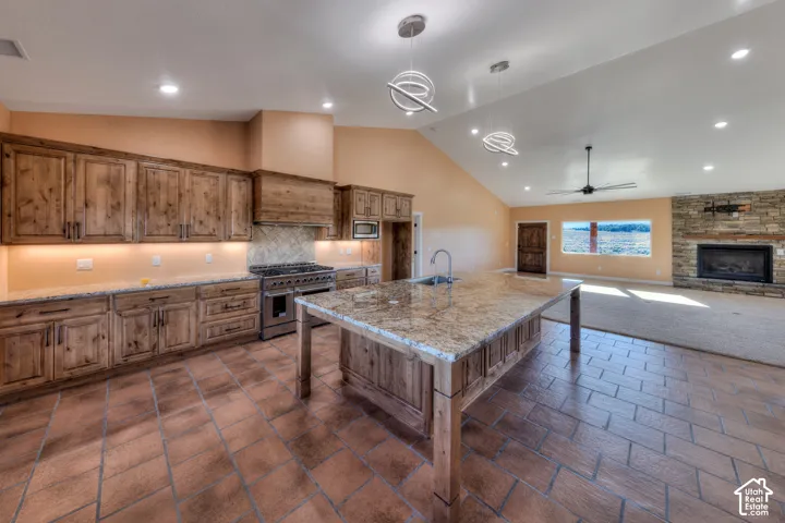 Kitchen featuring brown cabinets, a kitchen island with sink, recessed lighting, a kitchen bar, and high vaulted ceiling
