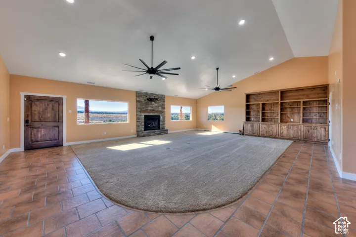 Unfurnished living room featuring a fireplace, recessed lighting, ceiling fan, vaulted ceiling, and dark carpet