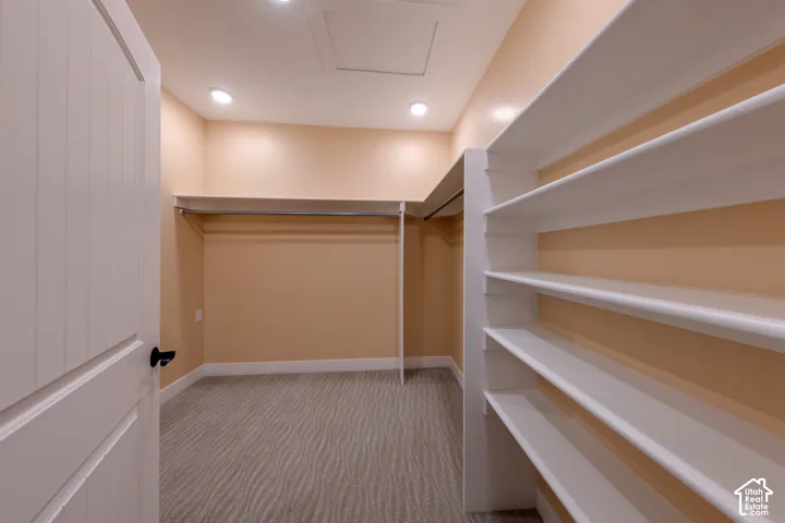 Walk in closet with light carpet and attic access