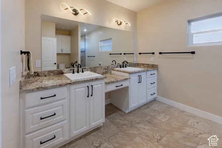 Bathroom with double vanity and baseboards