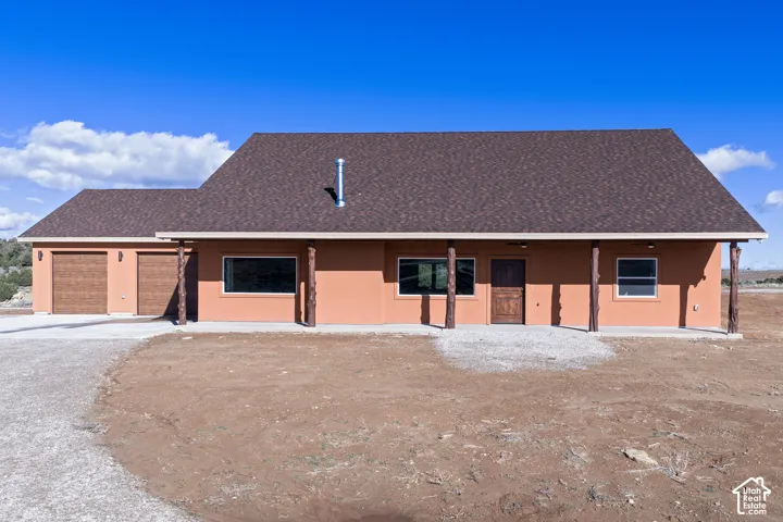 View of front of property featuring stucco siding, an attached garage, a shingled roof, and driveway