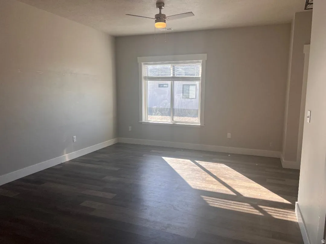 Spare room featuring dark wood finished floors, a textured ceiling, and ceiling fan