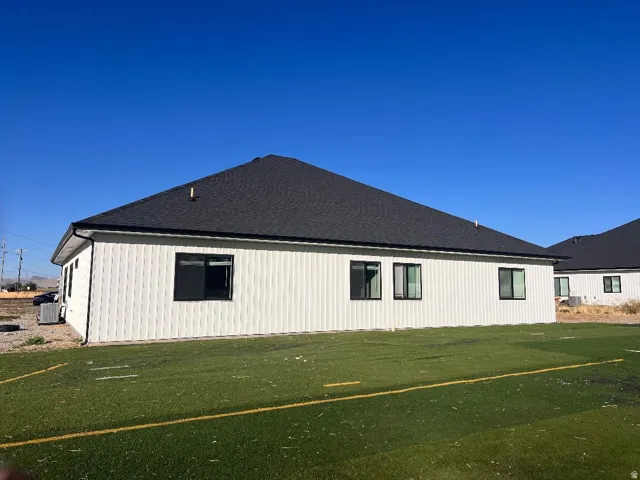 View of property exterior featuring a lawn and roof with shingles