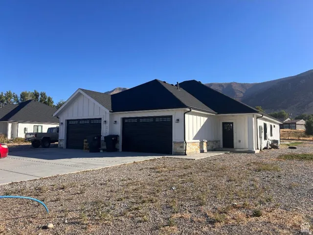 View of side of property featuring board and batten siding, stone siding, a garage, and concrete driveway