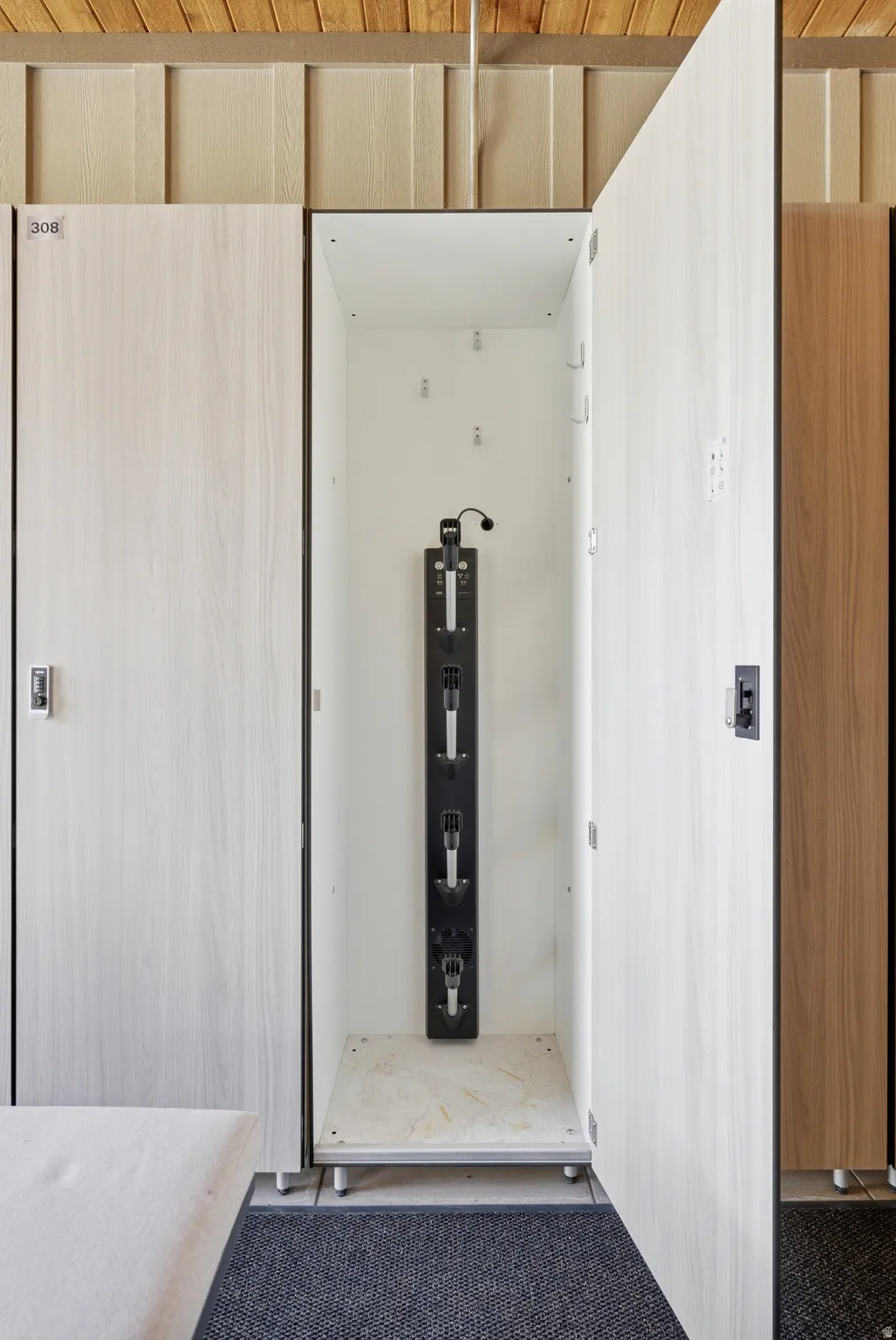 Individual locker storage featuring wood-finish paneling, an integrated hanging system, and a durable mat flooring