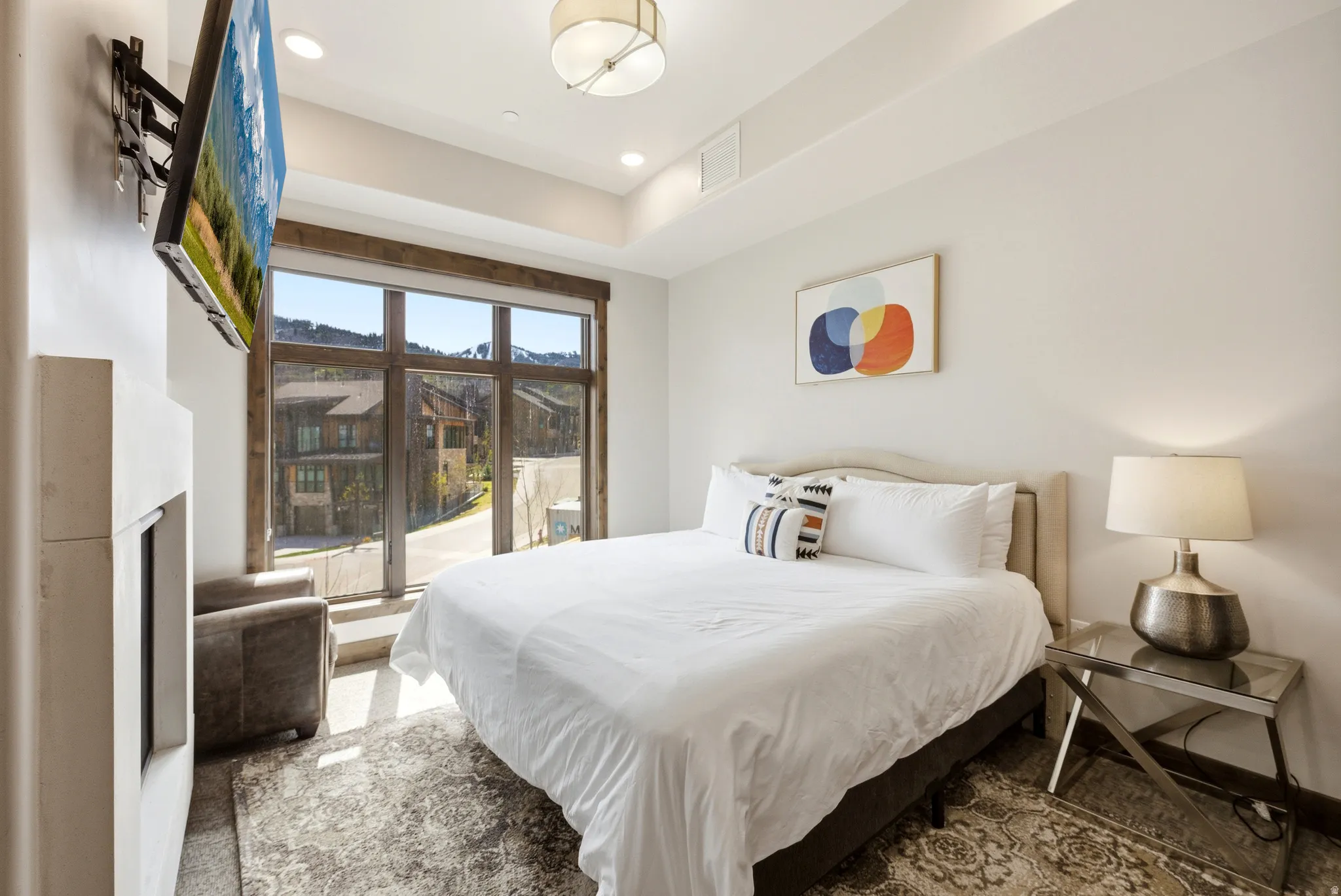 Bedroom featuring a built-in fireplace, large picture window with wooden framing, and recessed ceiling lighting