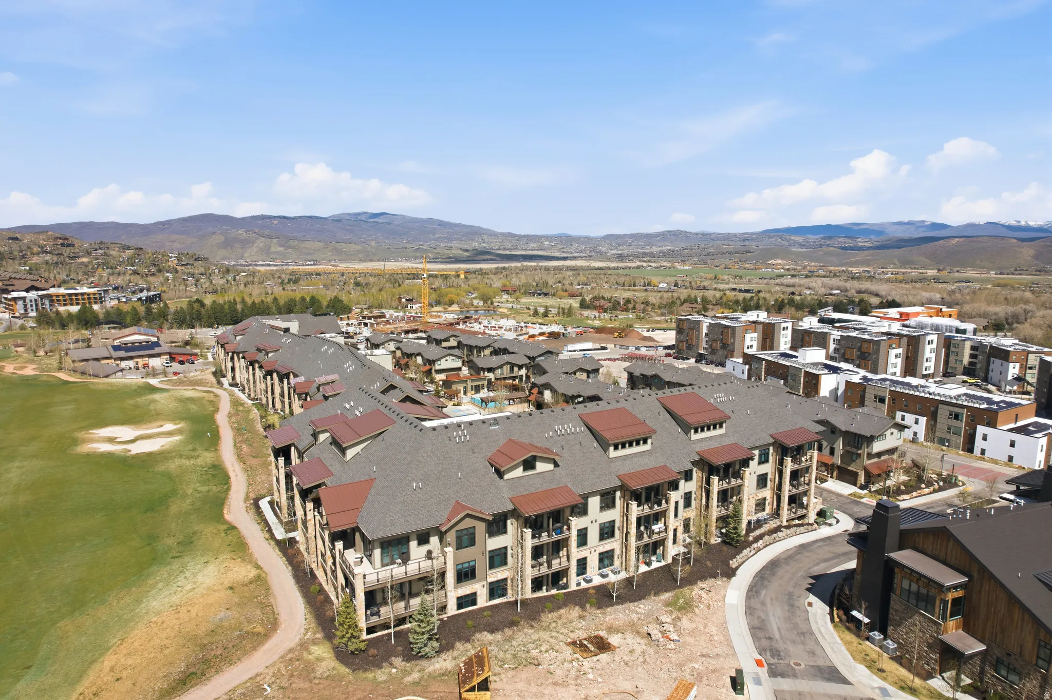 Contemporary multi-story residential building with private balconies and a brown shingle roof