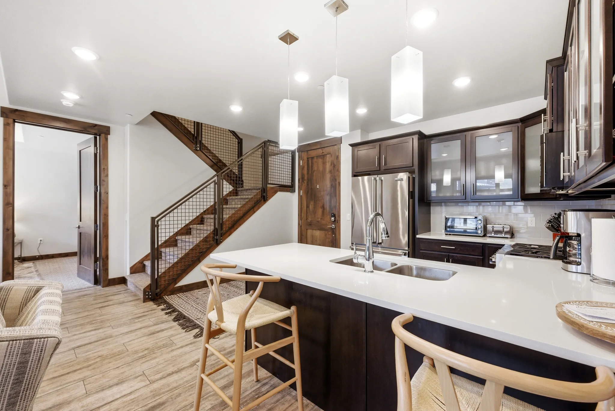 Kitchen featuring a large island with white countertop, dark wood-finish cabinetry, stainless steel refrigerator, and pendant lighting