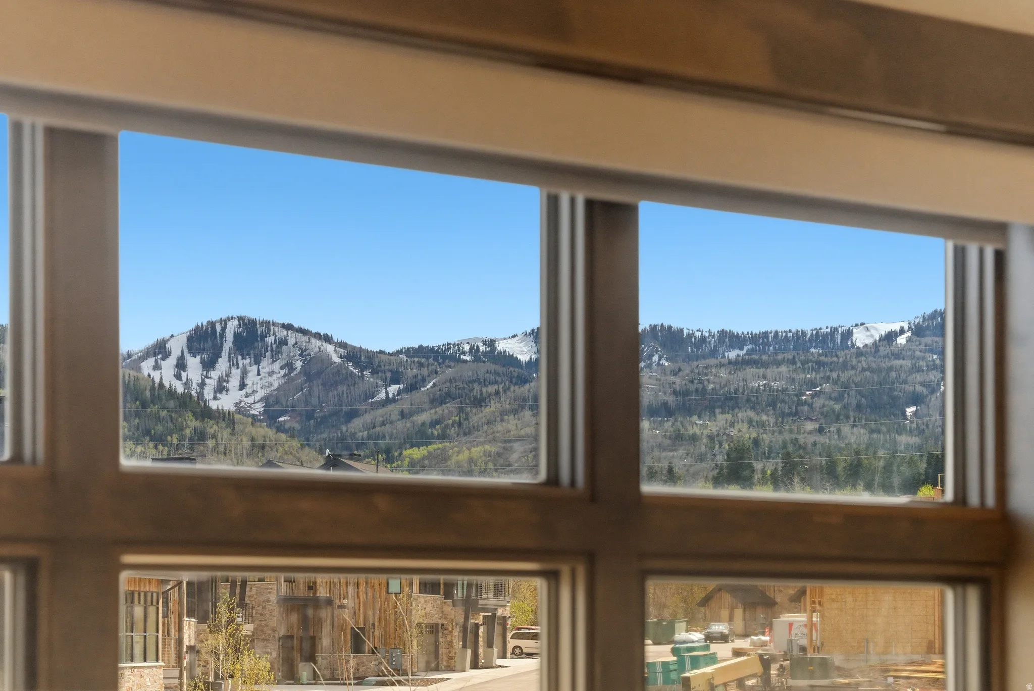 Expansive window framing snow-capped mountains and verdant trees