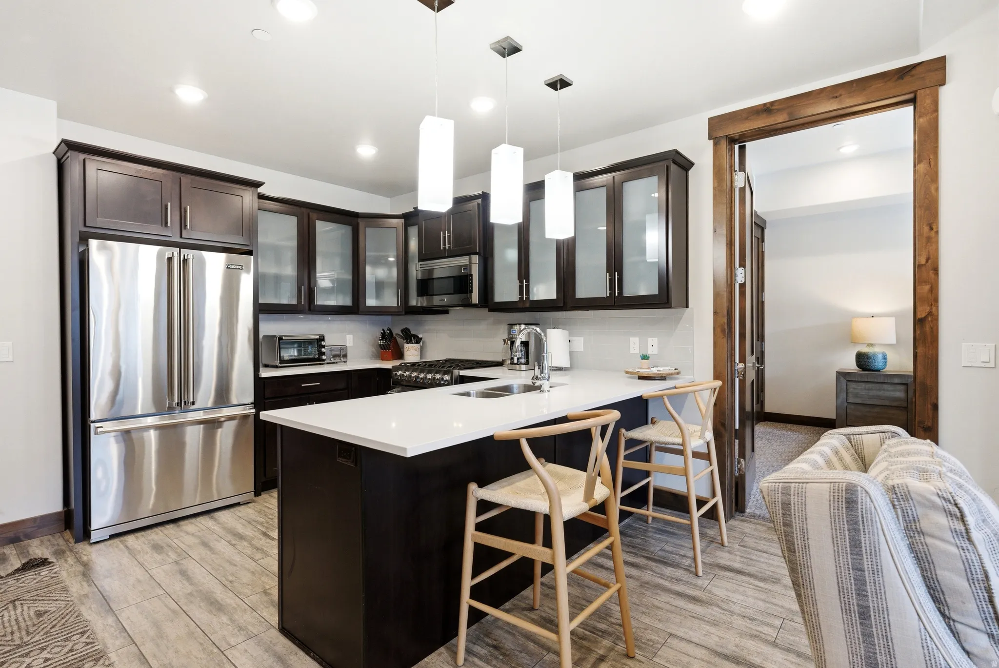 Modern kitchen featuring dark wood cabinetry, stainless steel appliances, a center island with a white countertop, and recessed lighting