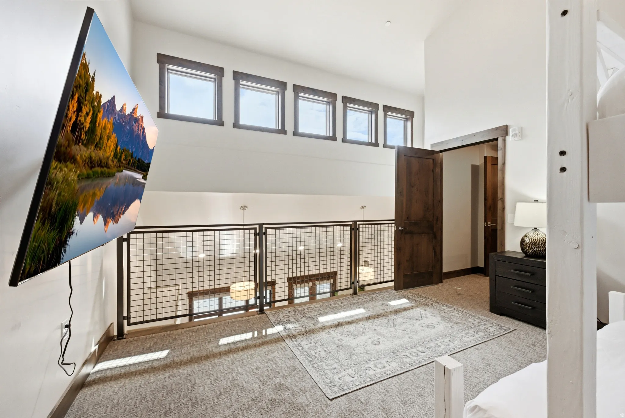 Loft area featuring vaulted ceilings, a dark wood-finish door, and metal grid railing overlooking the lower level