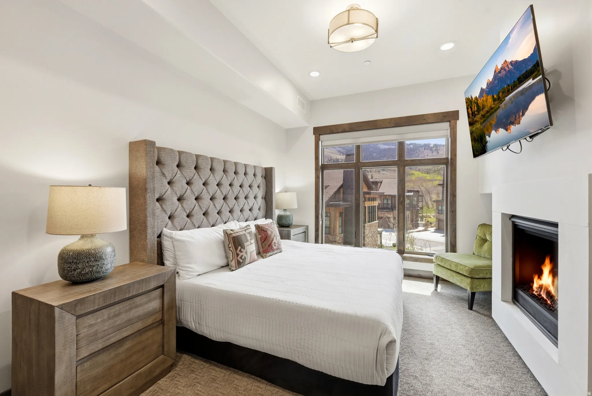 Plush carpeted room featuring an integrated fireplace, large window with outdoor scenery, recessed lighting, and a contemporary ceiling fixture