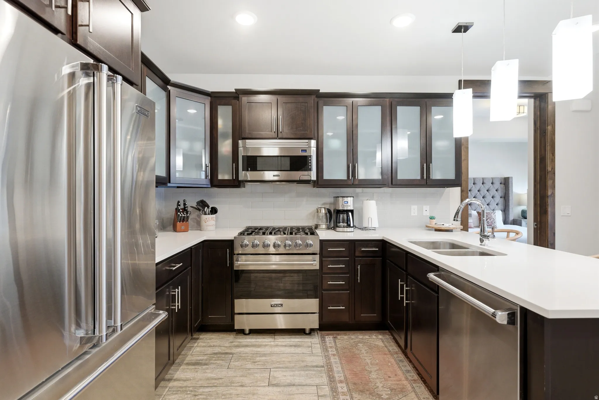 Modern kitchen featuring dark wood cabinetry, stainless steel appliances, white countertops, and a subway tile backsplash