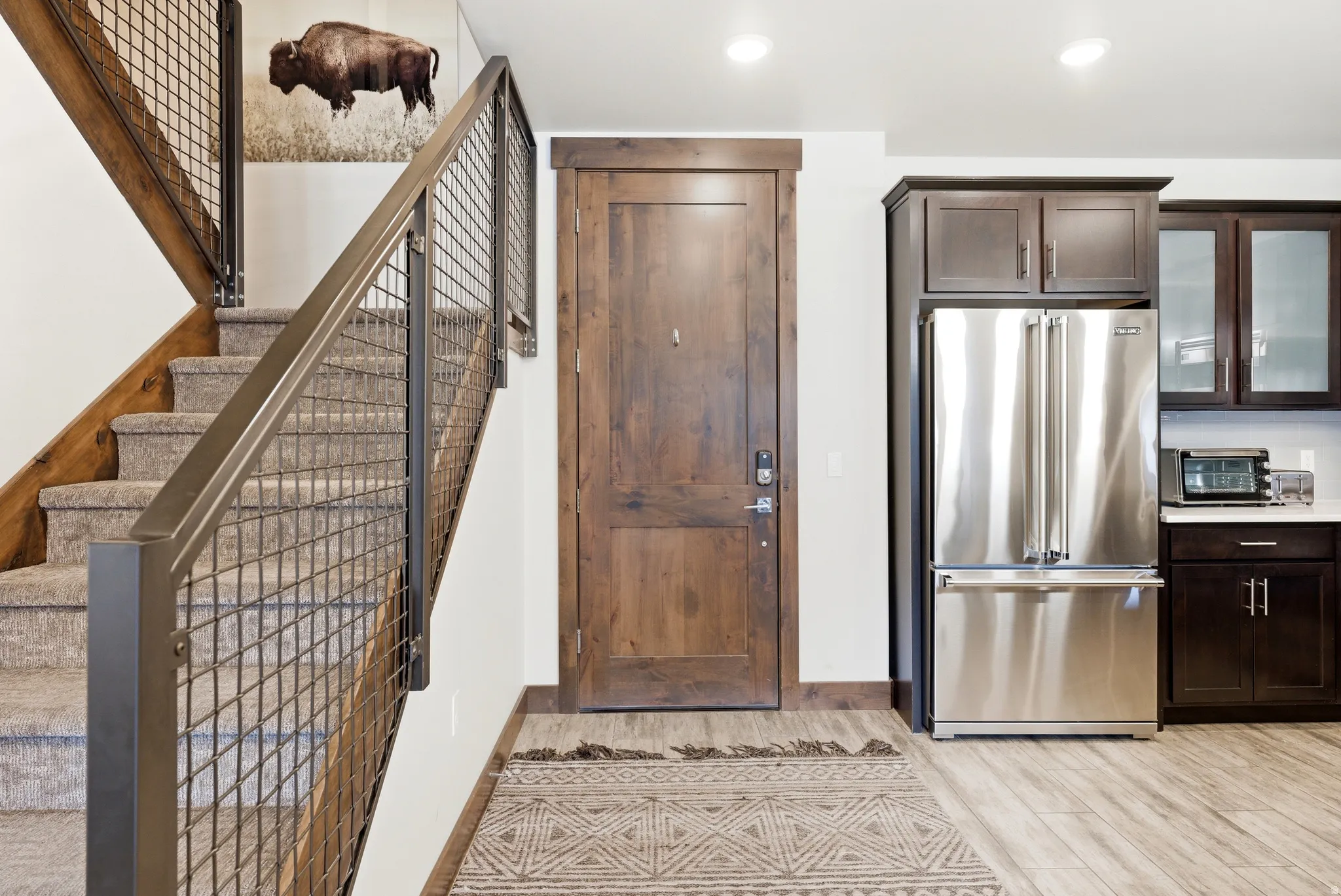 Staircase with industrial-style metal grid railing and wood-finish handrail