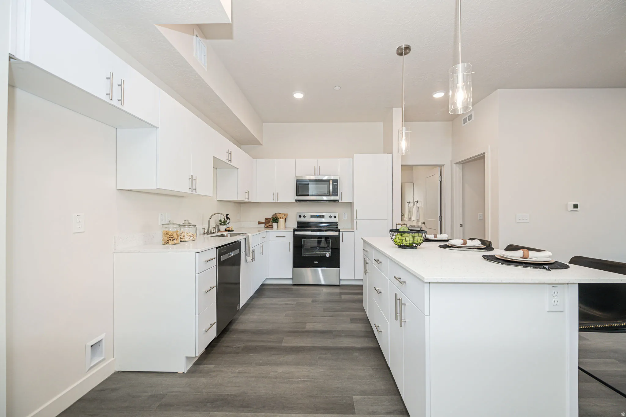 Kitchen featuring a kitchen bar, appliances with stainless steel finishes, white cabinetry, a kitchen island, and dark wood finished floors