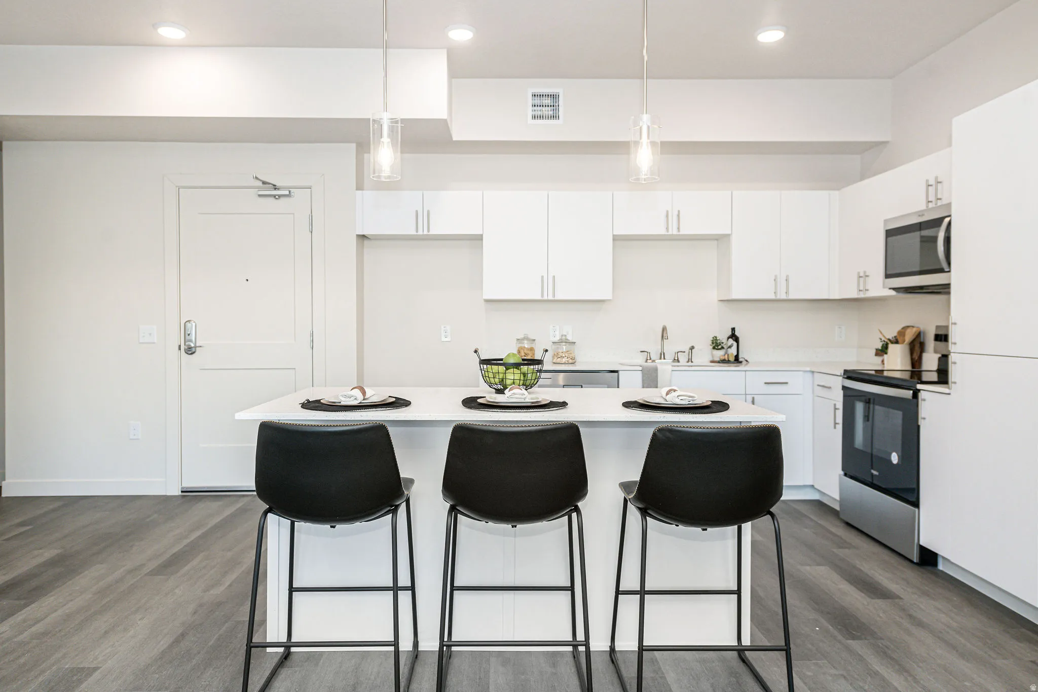 Kitchen with white cabinetry, appliances with stainless steel finishes, a breakfast bar area, pendant lighting, and a center island
