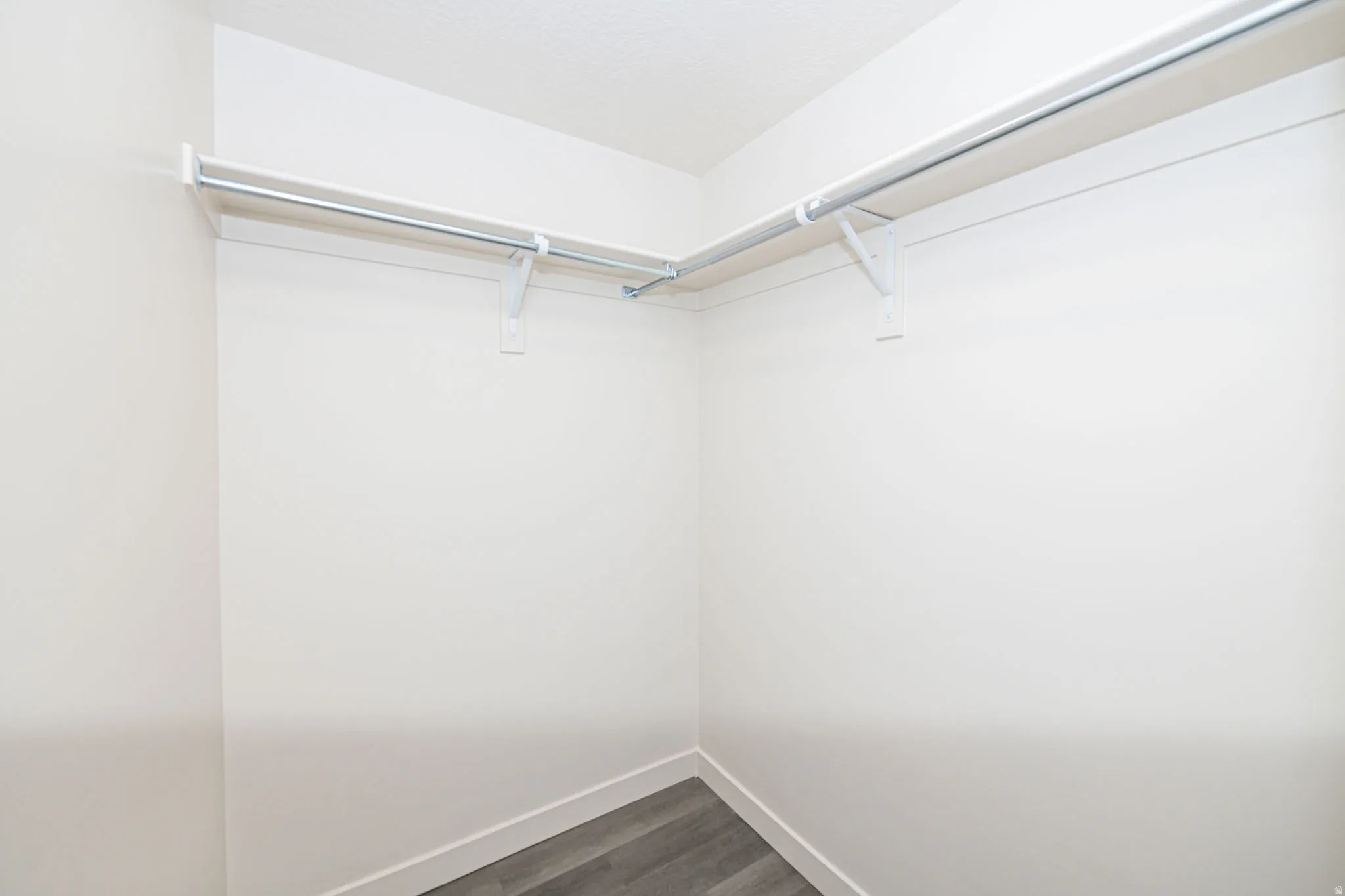 Walk in closet with dark wood finished floors