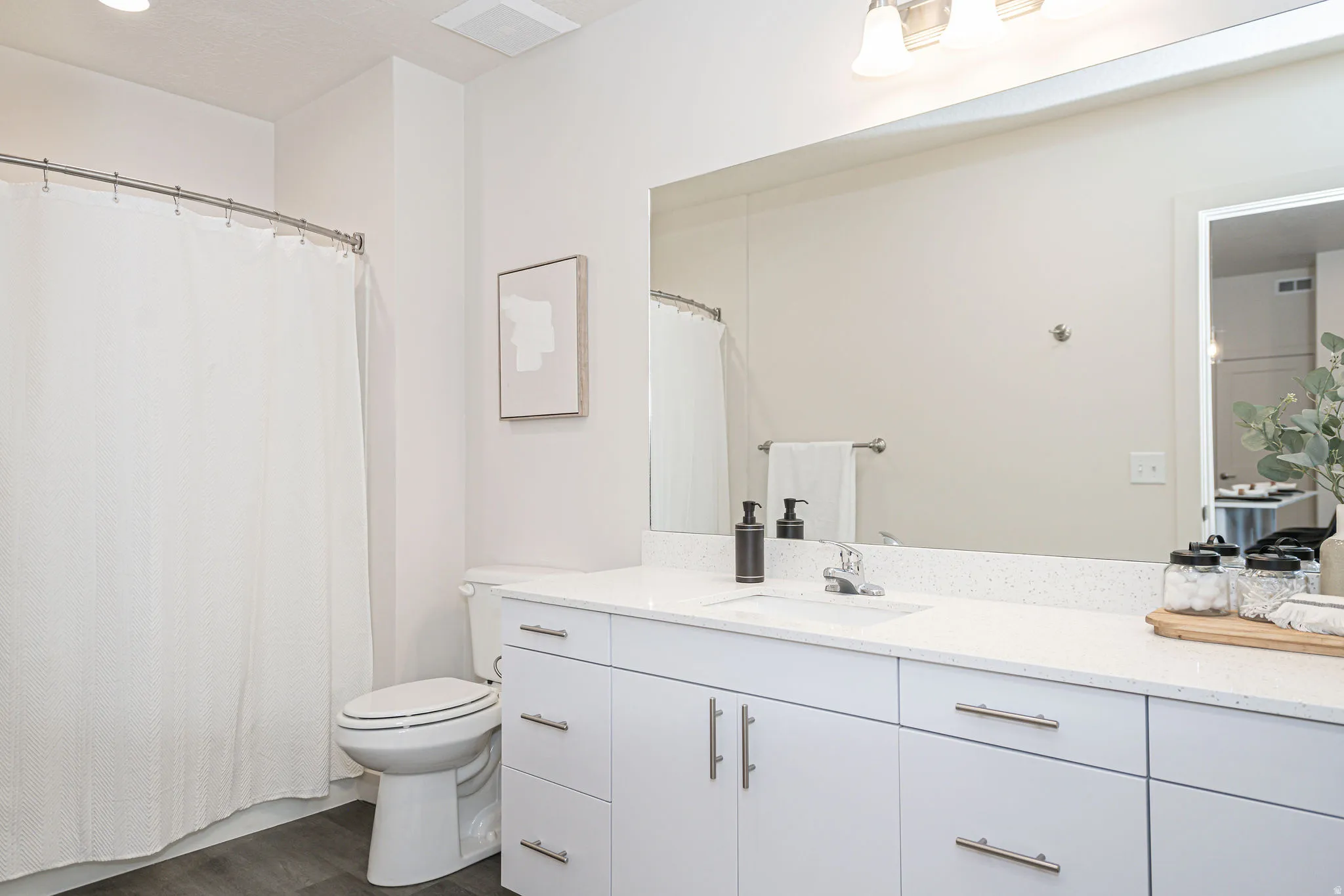 Bathroom with vanity, curtained shower, and dark wood-style floors