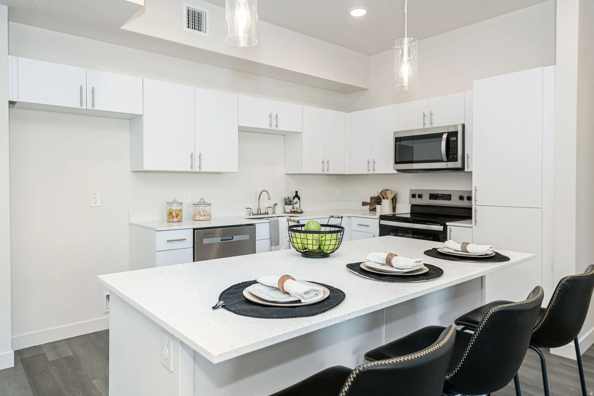 Kitchen featuring appliances with stainless steel finishes, white cabinets, dark wood finished floors, and decorative light fixtures