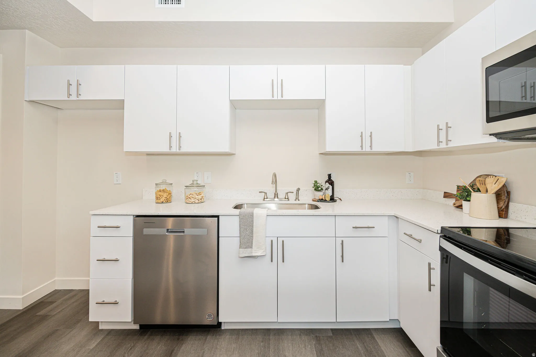 Kitchen with appliances with stainless steel finishes, white cabinetry, and dark wood-type flooring