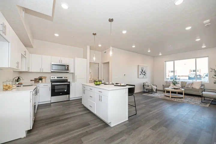 Kitchen featuring stainless steel appliances, a breakfast bar, white cabinets, pendant lighting, and a textured ceiling