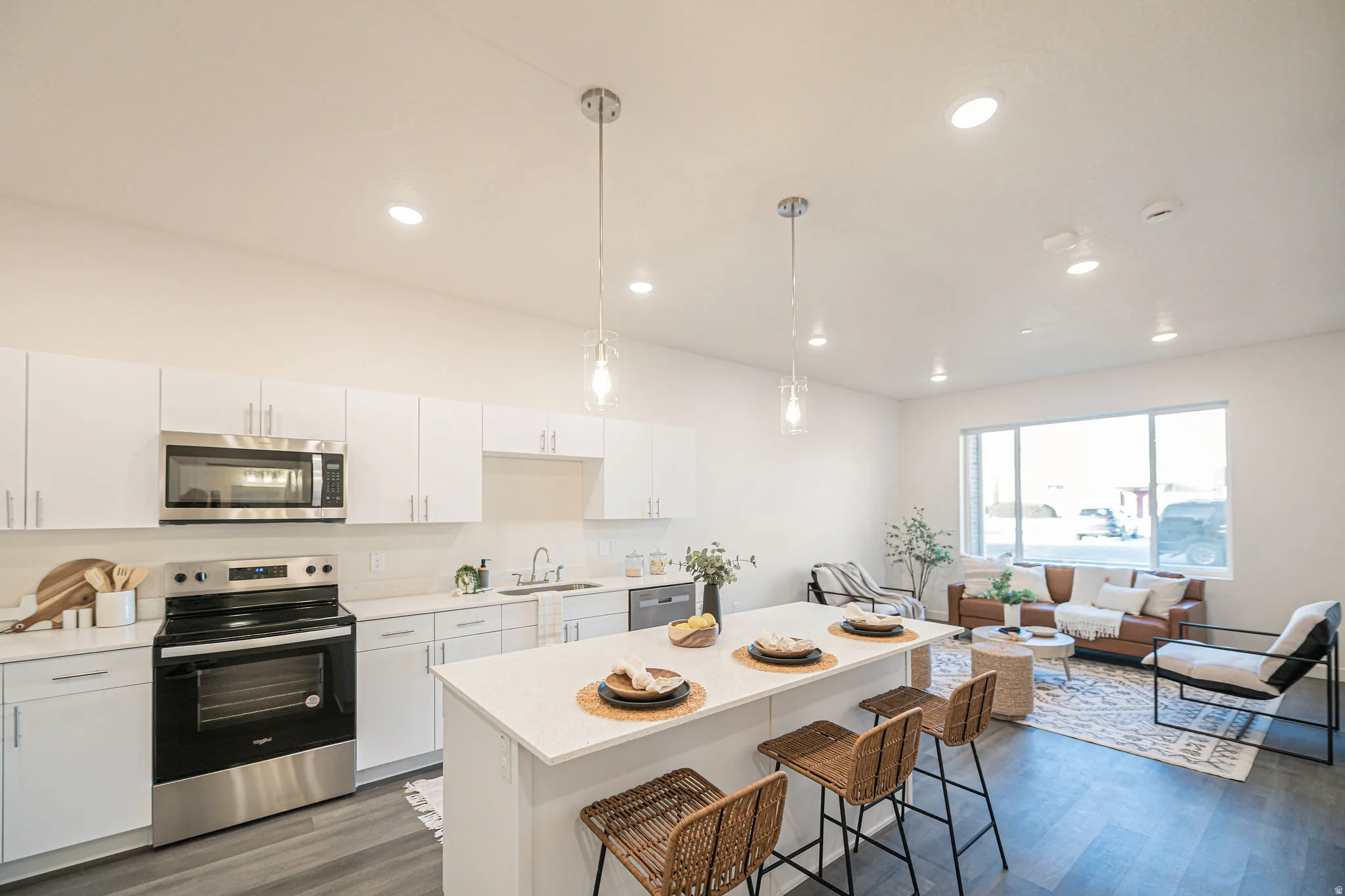 Kitchen featuring stainless steel appliances, white cabinets, pendant lighting, dark wood-style floors, and a kitchen breakfast bar