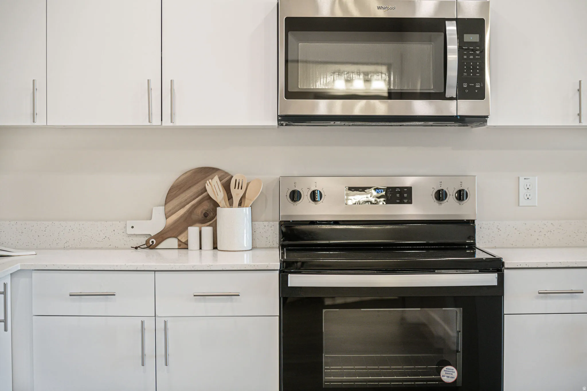 Kitchen featuring appliances with stainless steel finishes, white cabinetry, and light stone countertops