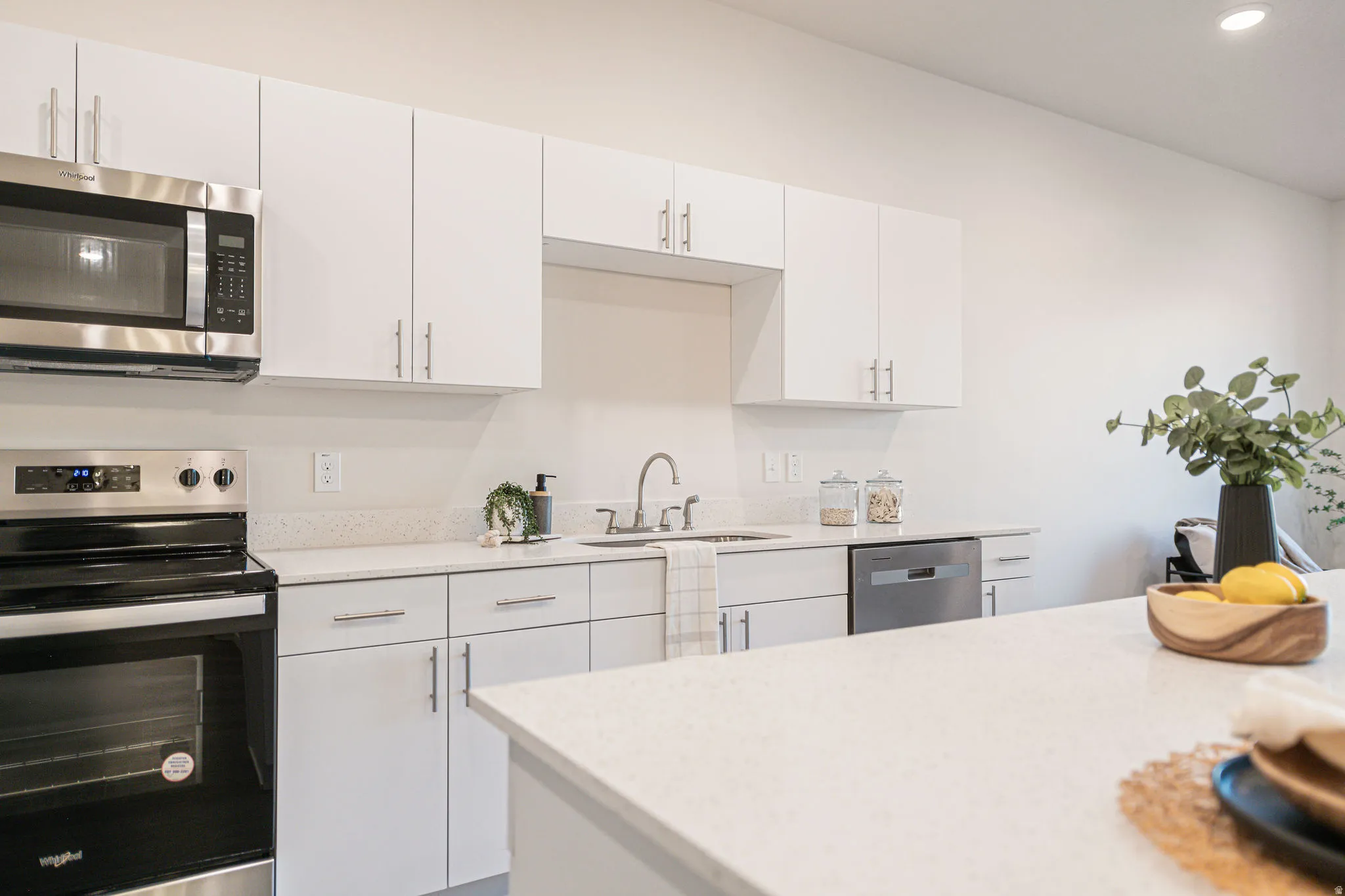 Kitchen featuring stainless steel appliances, white cabinetry, light stone counters, and recessed lighting