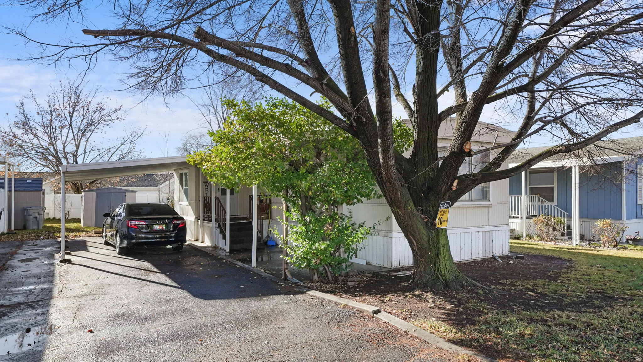 View of side of home featuring a carport, driveway, and a storage shed