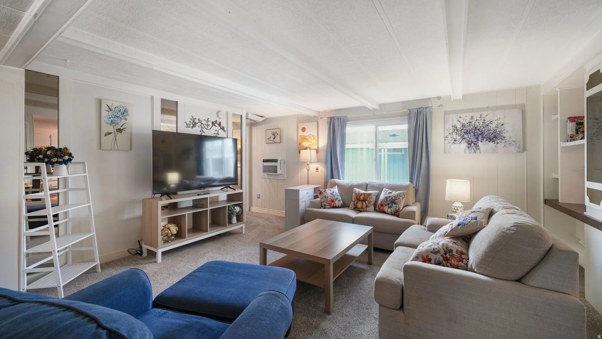 Living room featuring carpet flooring, beam ceiling, a textured ceiling, and an AC wall unit