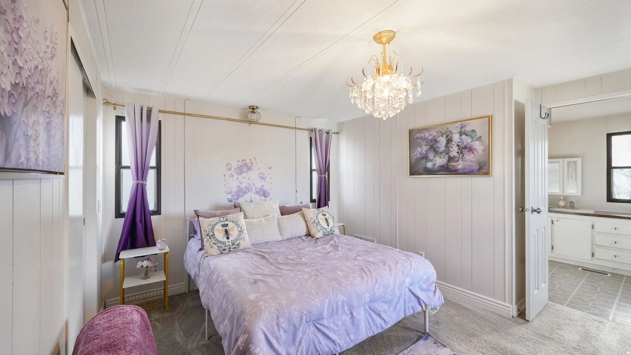 Bedroom with a chandelier, light carpet, wood walls, and connected bathroom